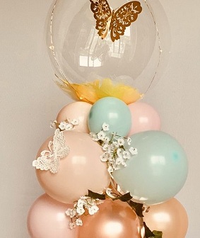 Cluster of balloons with bobo balloon resting on it with butterflies and flowers