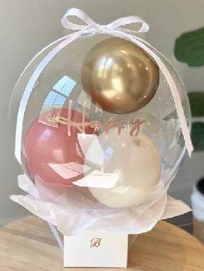 Happy bobo balloon stuffed with gold white pink balloons styled on a box