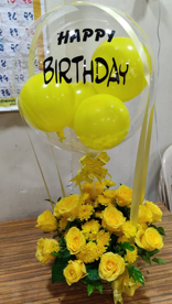 Transparent Balloon Printed Happy Birthday stuffed with yellow balloons Tied with yellow ribbons to a basket of 12 yellow roses