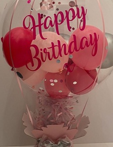 Happy birthday printed transparent balloon with pink and silver stuffed balloons on a pink decorated box with 10 dairy milk chocolates